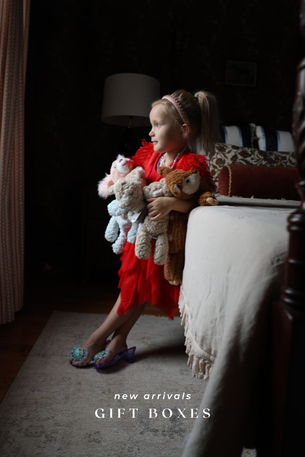 Child holding teddy bears in a room with 'New Arrivals Gift Boxes' text.